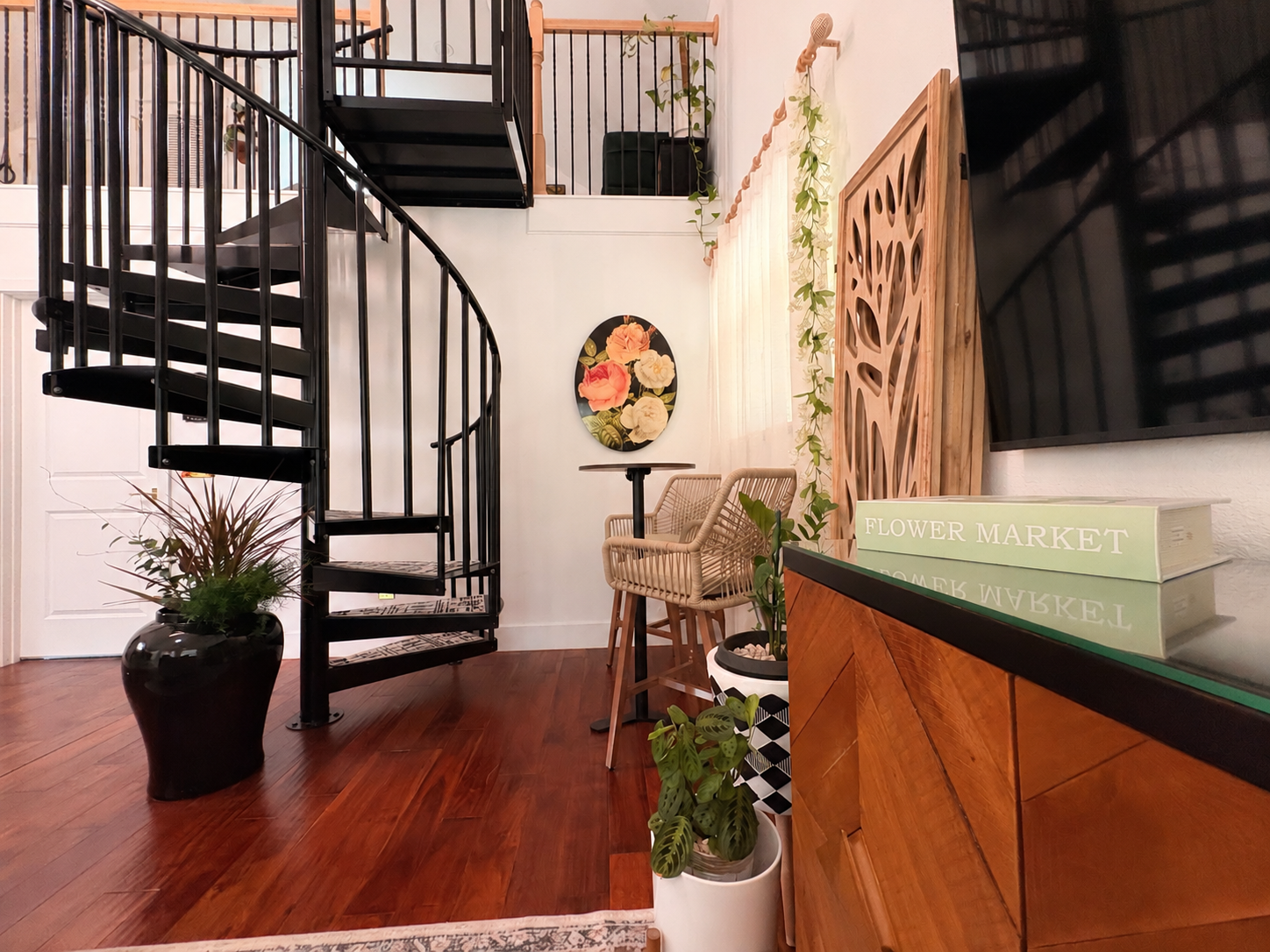 The matte black spiral staircase rising through two floors of Casa Bohemia, framed by living botanicals, warm walnut and soft daylight